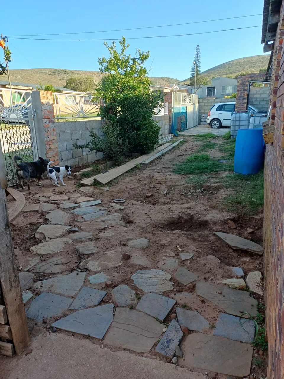 Before: uneven flagstone path on bare soil between the house and street gate