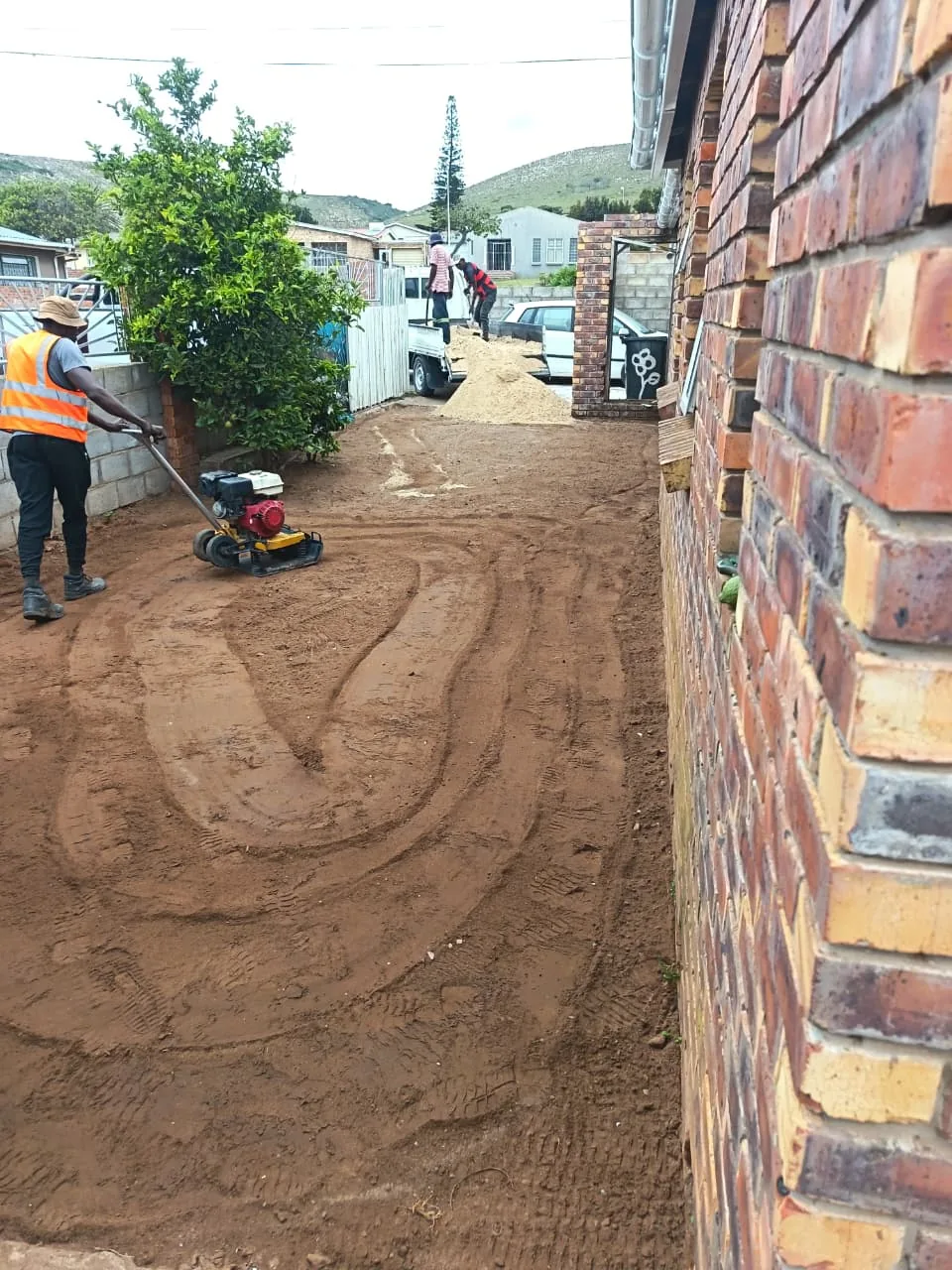 Worker compacting the sub-base with a plate compactor
