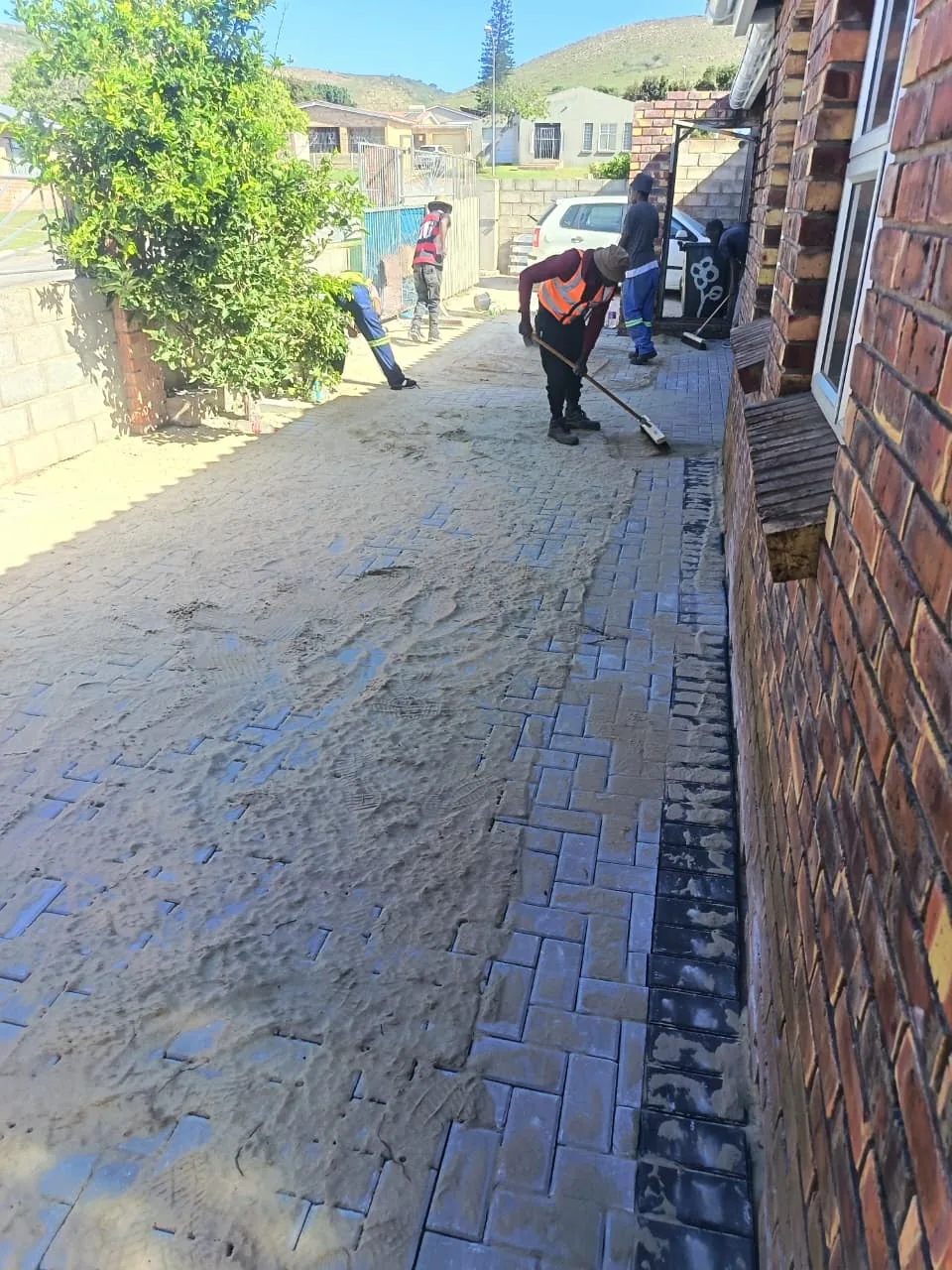 Team brushing jointing sand into finished paving